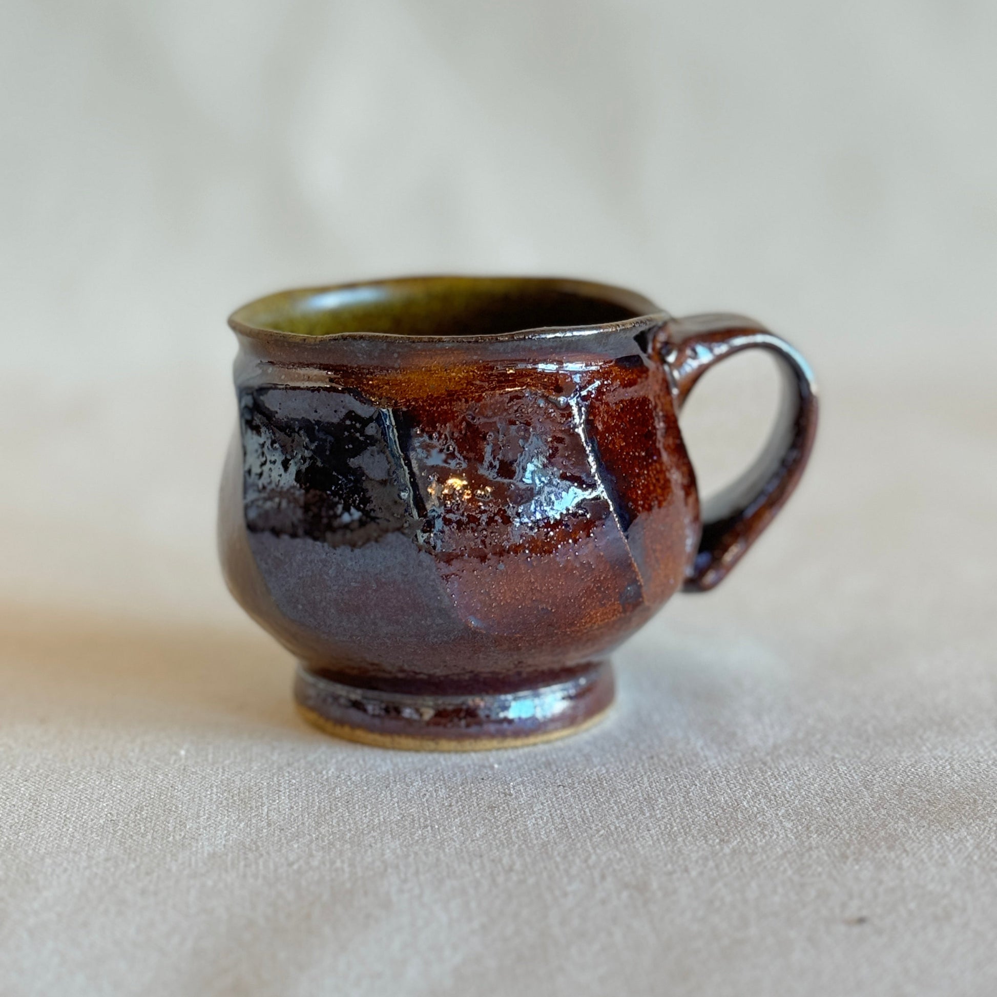 Brown/red ceramic mug on a beige surface