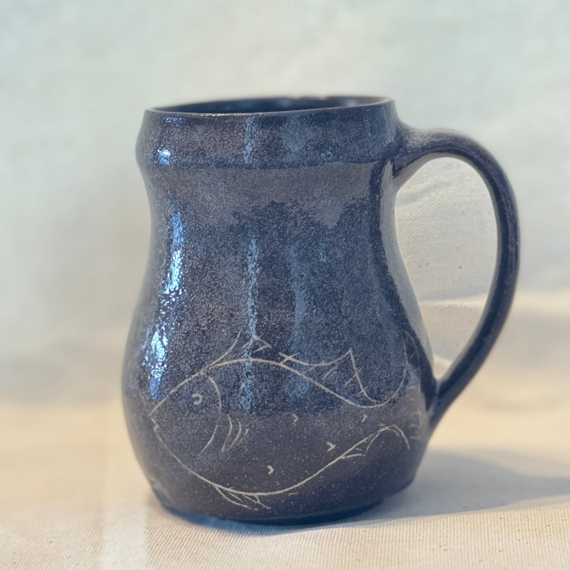 Brown ceramic mug with fish design on a white background
