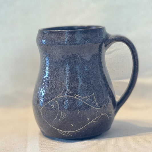 Brown ceramic mug with fish design on a white background
