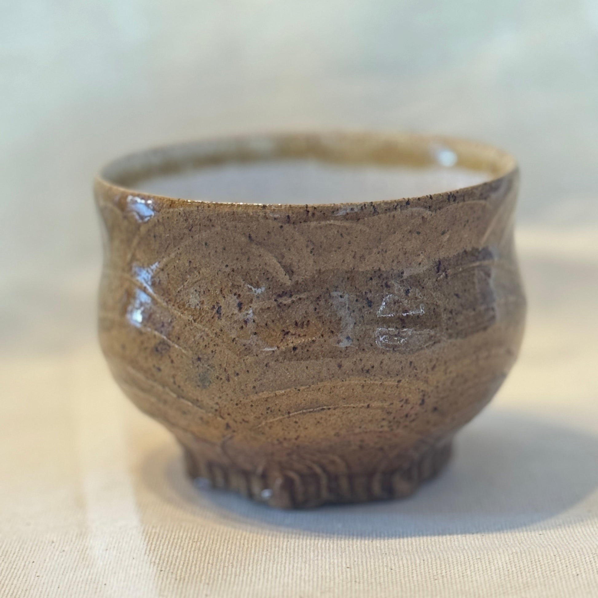 Brown ceramic cup with textured design on a light background