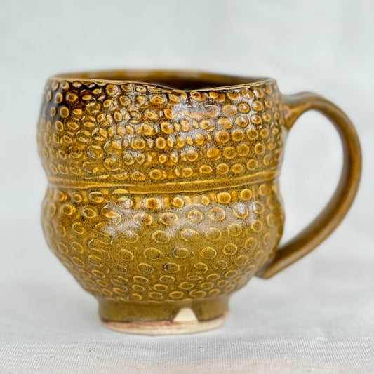 Brown ceramic mug with textured design on a light background