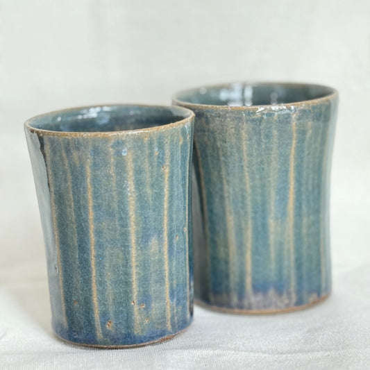 Two blue ceramic cups with a textured surface on a white background