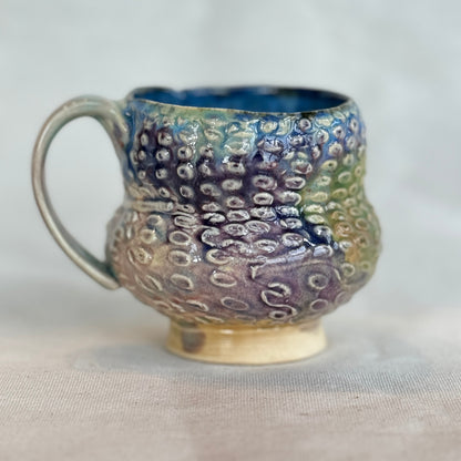 Handmade ceramic mug with textured surface on a light background
