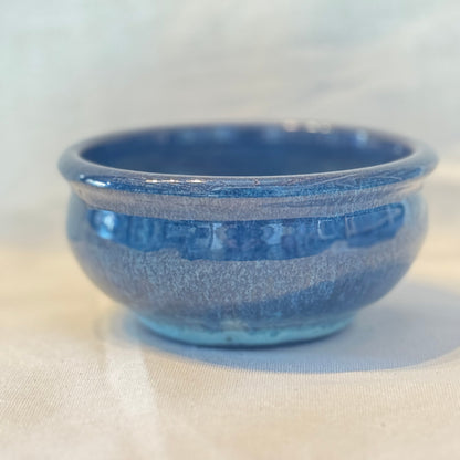 Blue ceramic bowl on a light beige surface with a white background