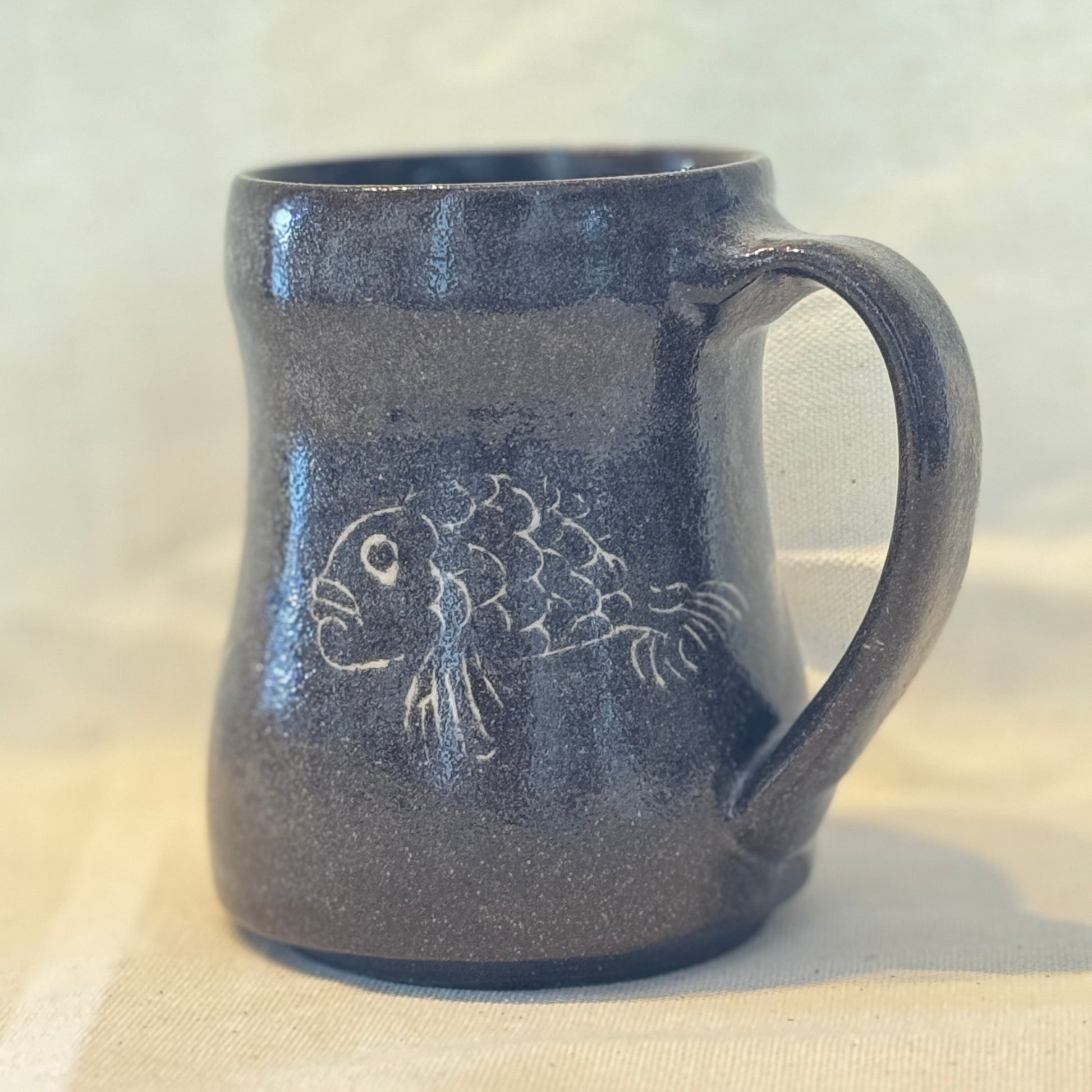 Blue ceramic mug with fish design on a white background