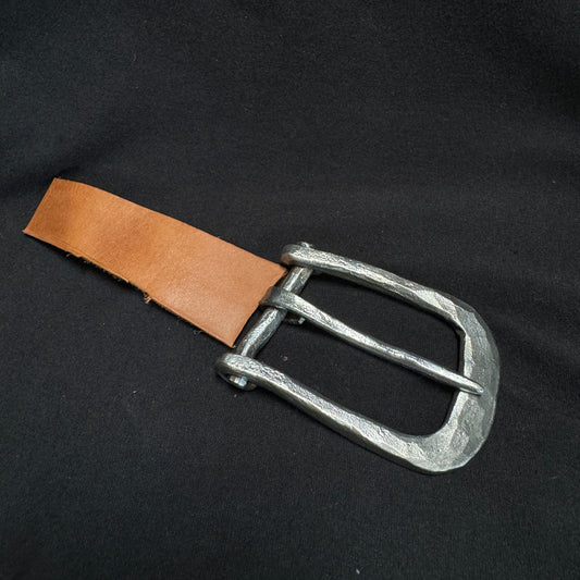 Metal belt buckle with brown leather strap on a black background