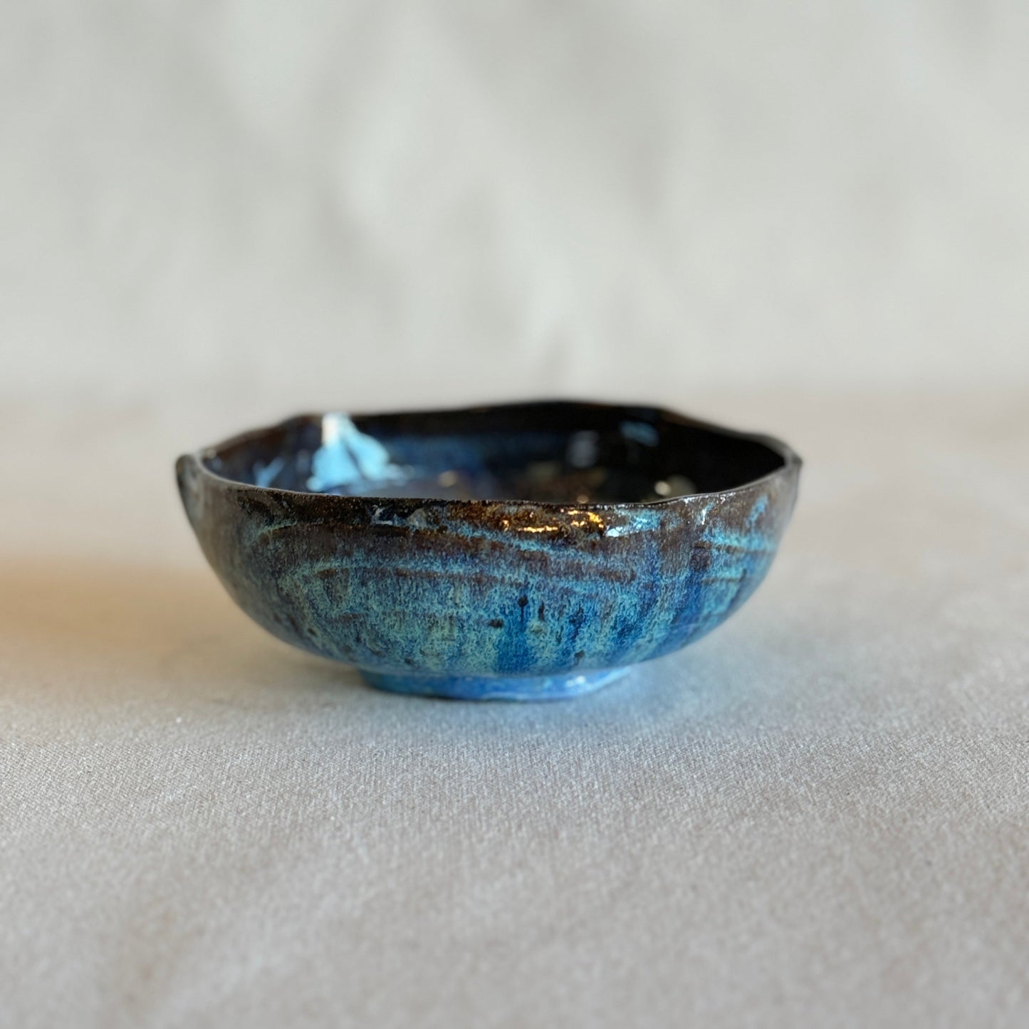 Small ceramic bowl with blue glaze on a light gray background