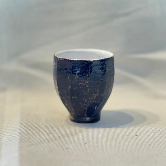 Small dark blue ceramic cup on a light fabric background