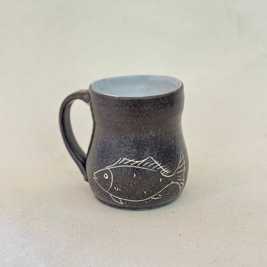 Ceramic mug with fish design on a plain background