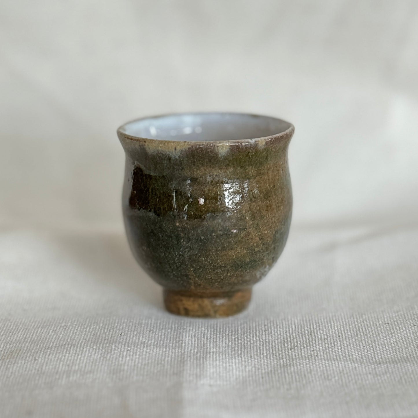 Small ceramic cup with a textured surface on a white fabric background