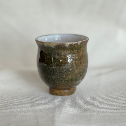 Small ceramic cup with a textured surface on a white fabric background