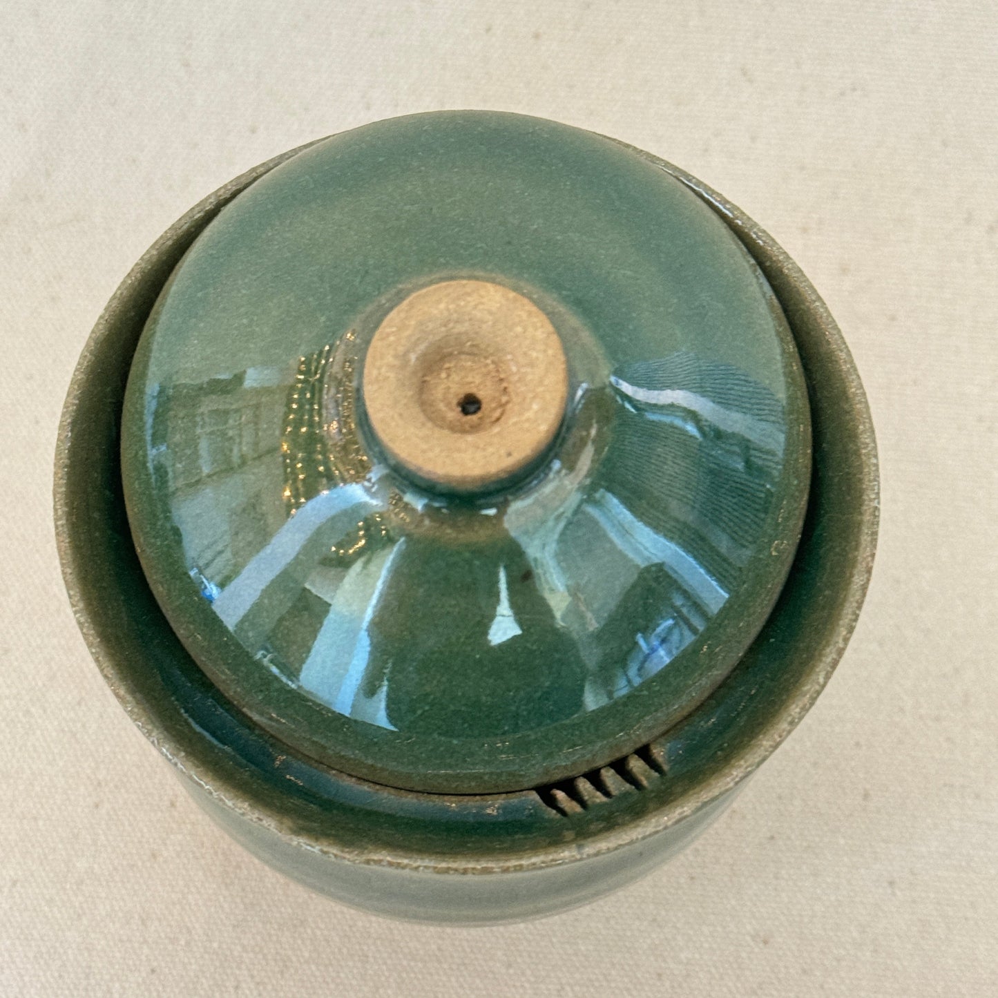 Ceramic lidded cup with a textured surface on a beige background