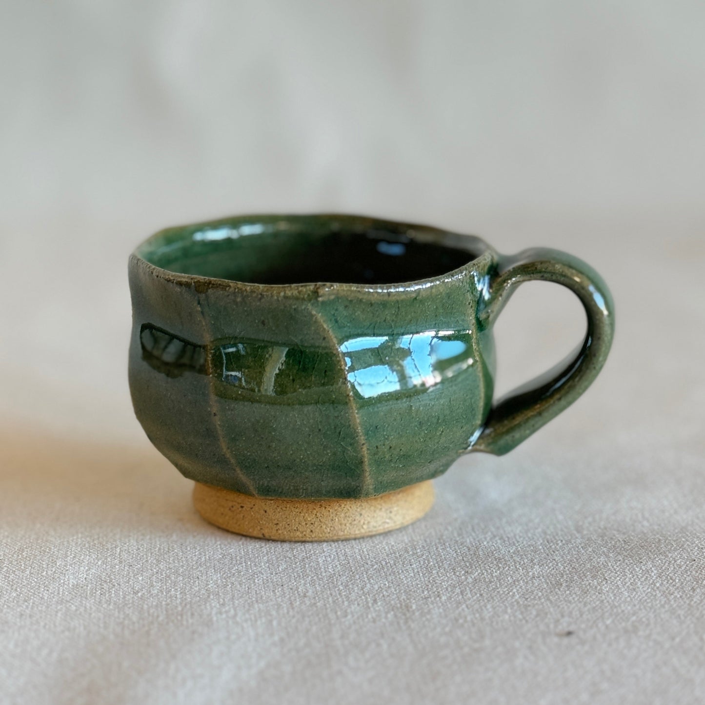 Green ceramic mug on a beige background