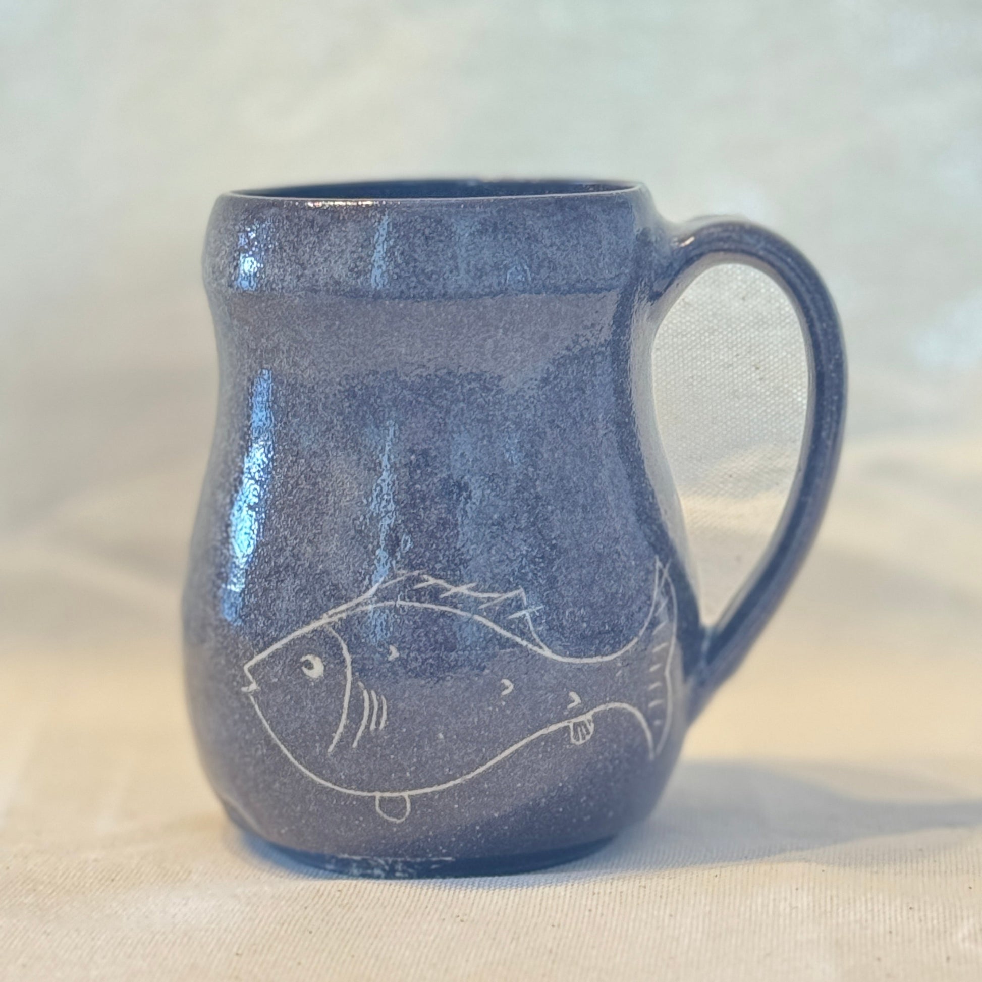 Blue ceramic mug with fish design on a white background