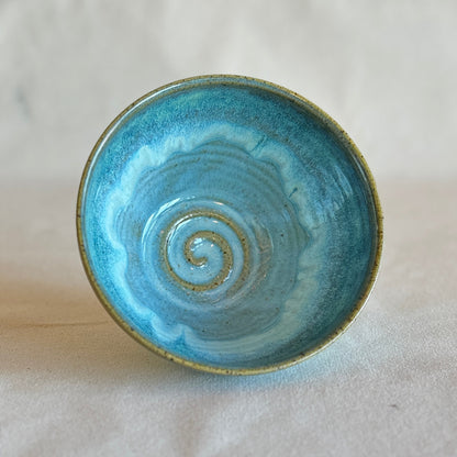 Blue ceramic bowl with a spiral design on a light gray background