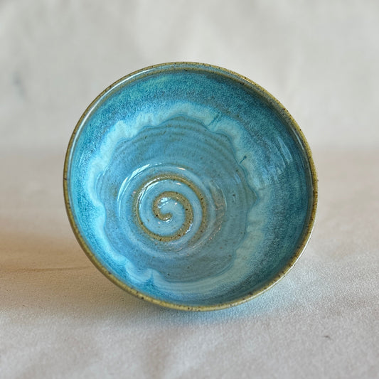 Blue ceramic bowl with a spiral design on a light gray background