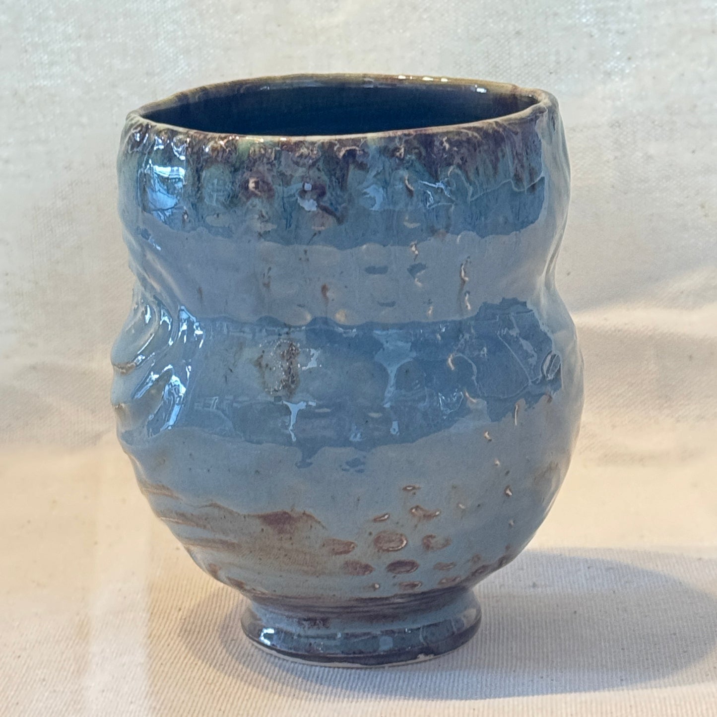 Blue ceramic vase on a textured white surface