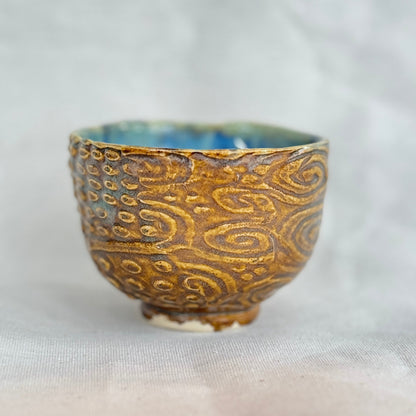 Ceramic cup with gold patterns on a white background
