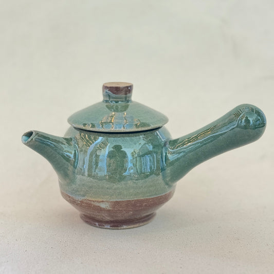 Green ceramic teapot on a white background