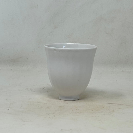 White ceramic tea cup on a textured white surface