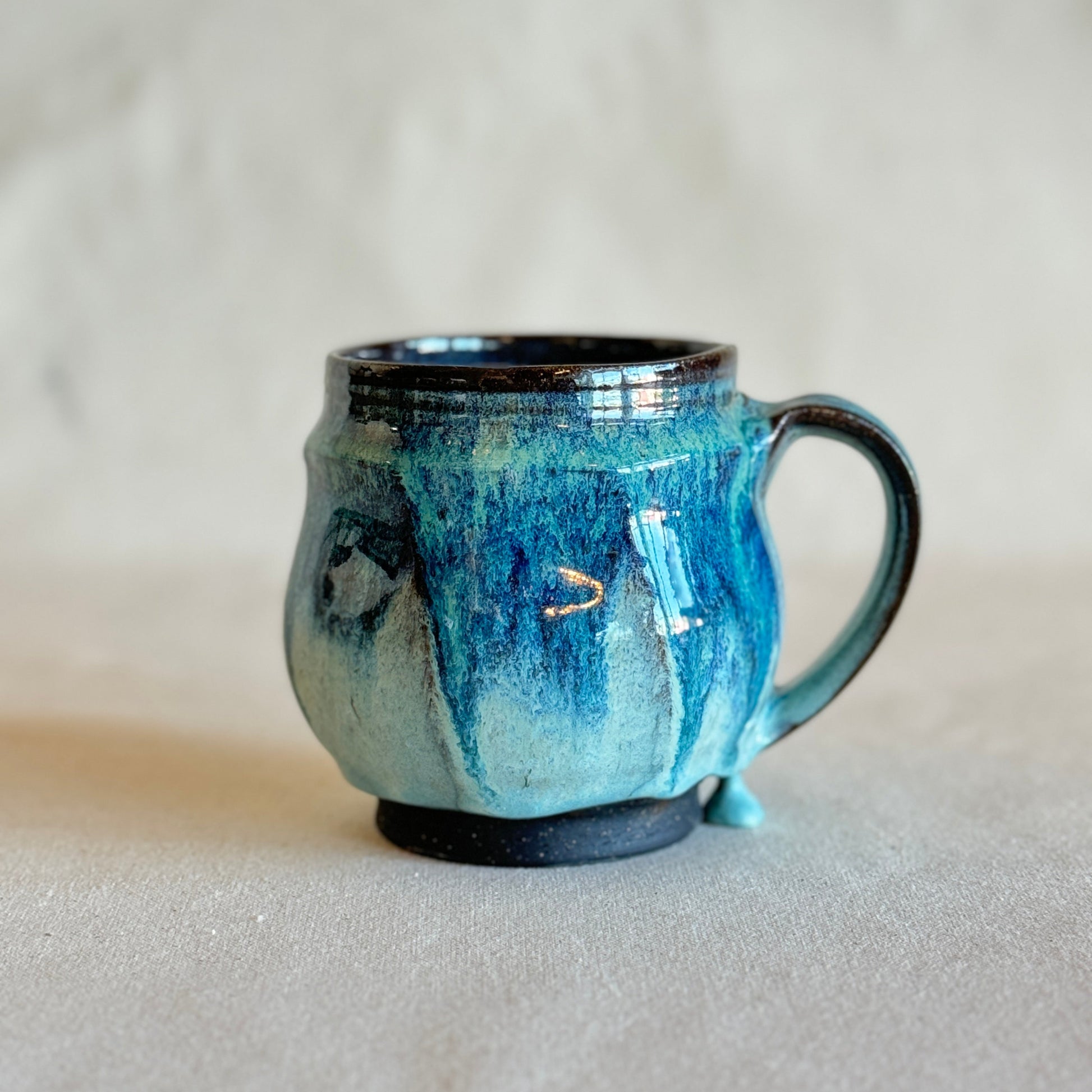 Blue ceramic mug with black rim and handle on a light gray background