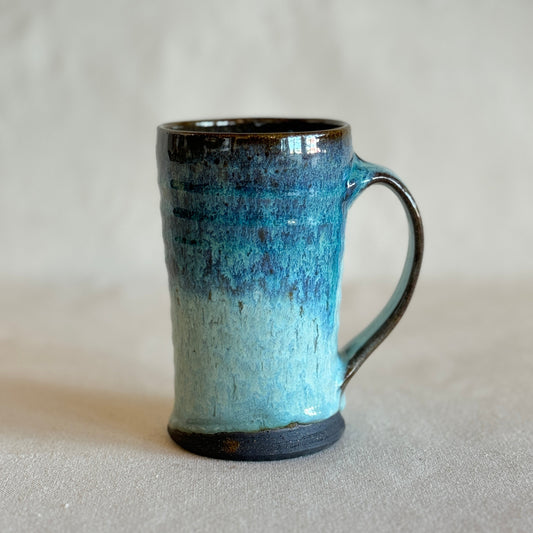 Blue ceramic mug with a gradient finish on a light gray background