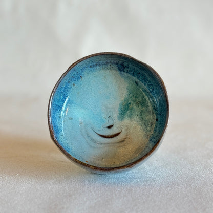 Ceramic matcha bowl with blue and green glaze on a white background