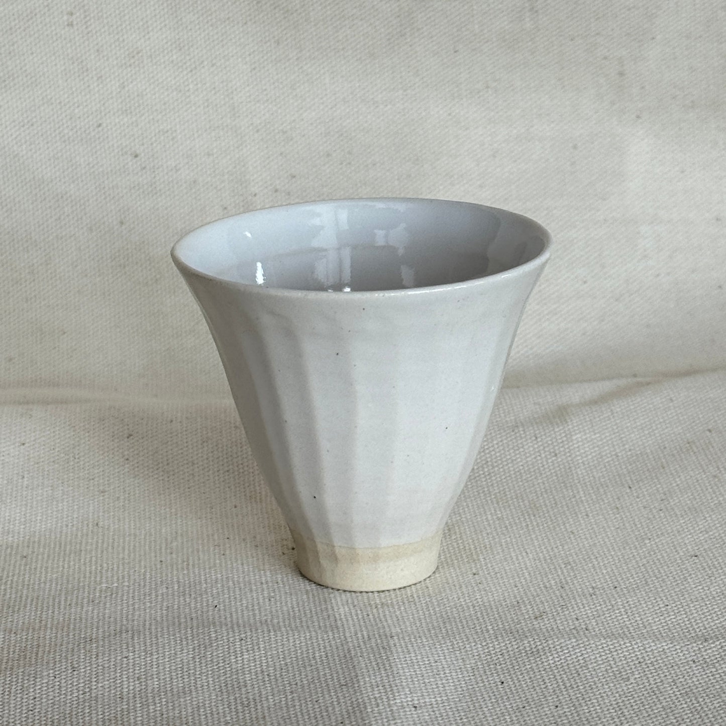White ceramic funnel on a textured beige background