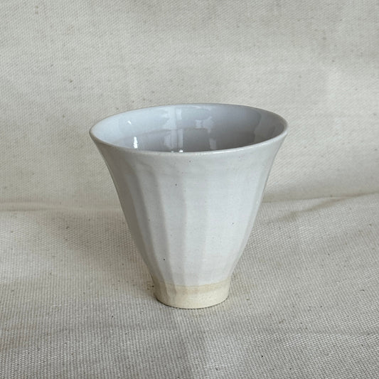 White ceramic funnel on a textured beige background