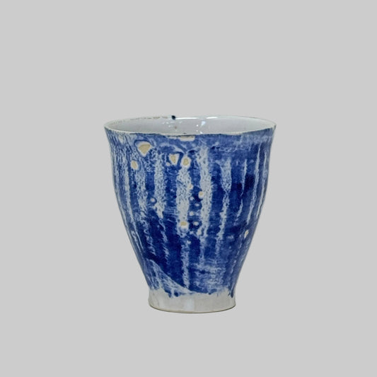 Ceramic cup with blue and white pattern on a light wooden surface