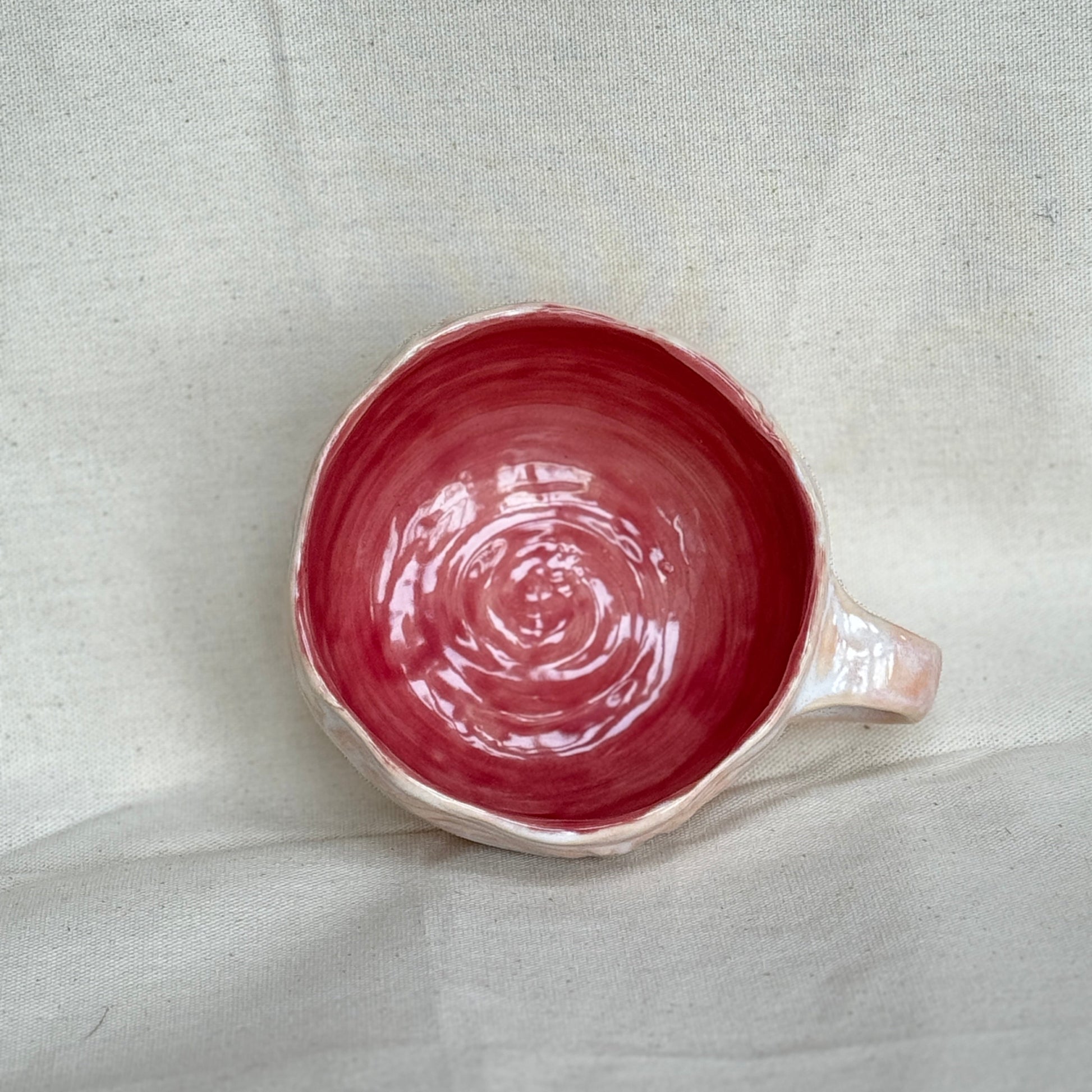 pink ceramic mug with a handle on a light gray fabric background