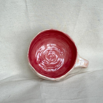 pink ceramic mug with a handle on a light gray fabric background