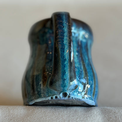Blue ceramic vase on a light gray surface with a neutral background
