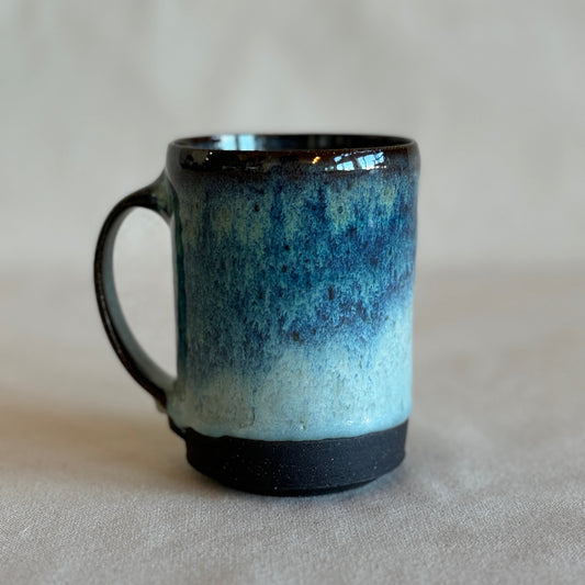 Ceramic mug with blue and black gradient on a neutral background