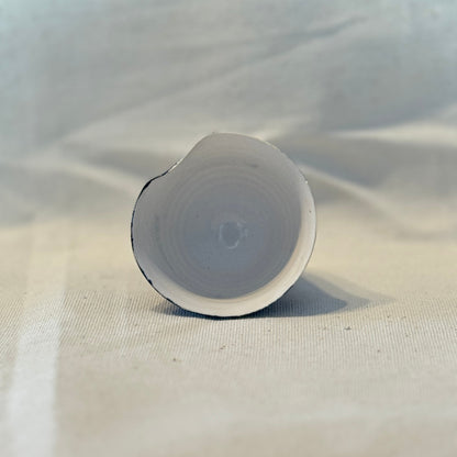 White cylindrical object on a textured beige surface with a light gray background