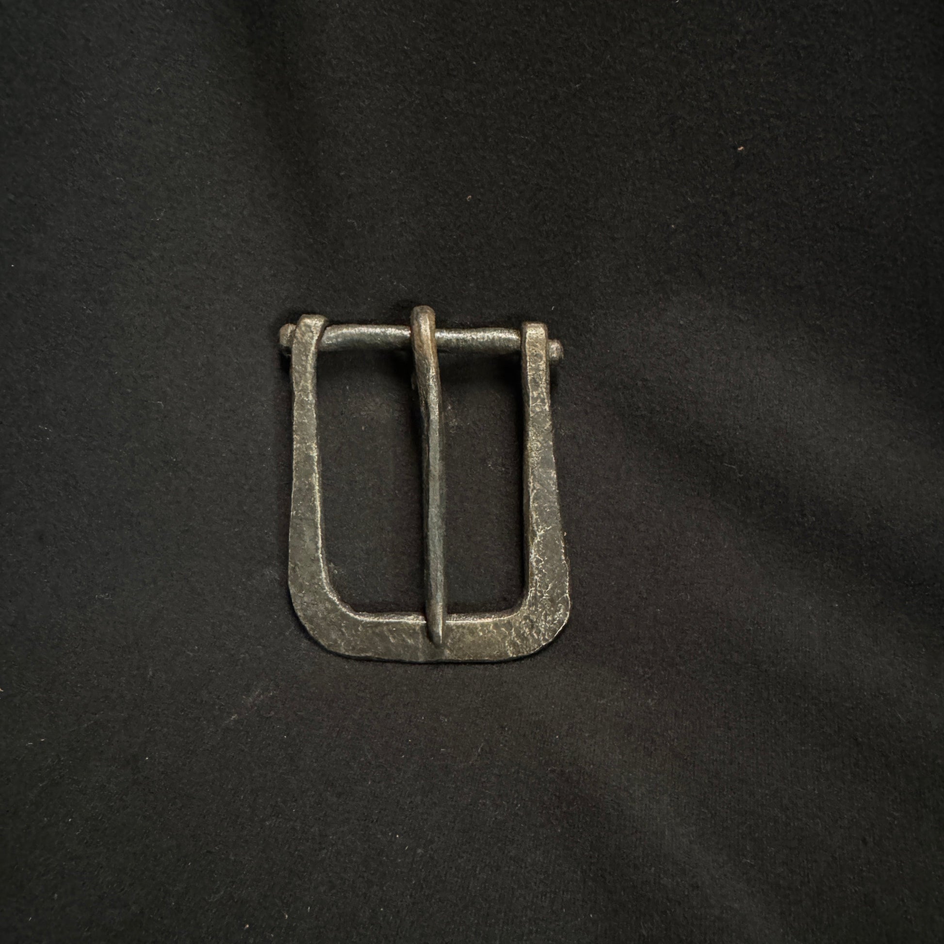 Metallic belt buckle on a black fabric background