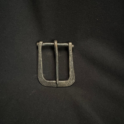 Metallic belt buckle on a black fabric background