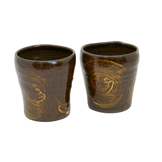 Two brown ceramic cups with swirling patterns on a white background