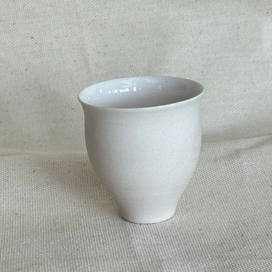 White ceramic cup on a textured gray fabric background