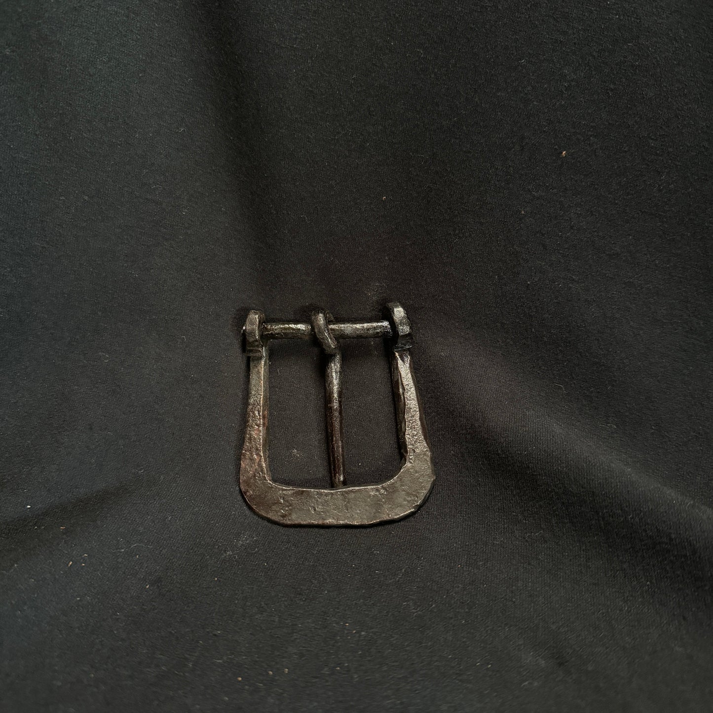 Metallic belt buckle on a dark fabric background