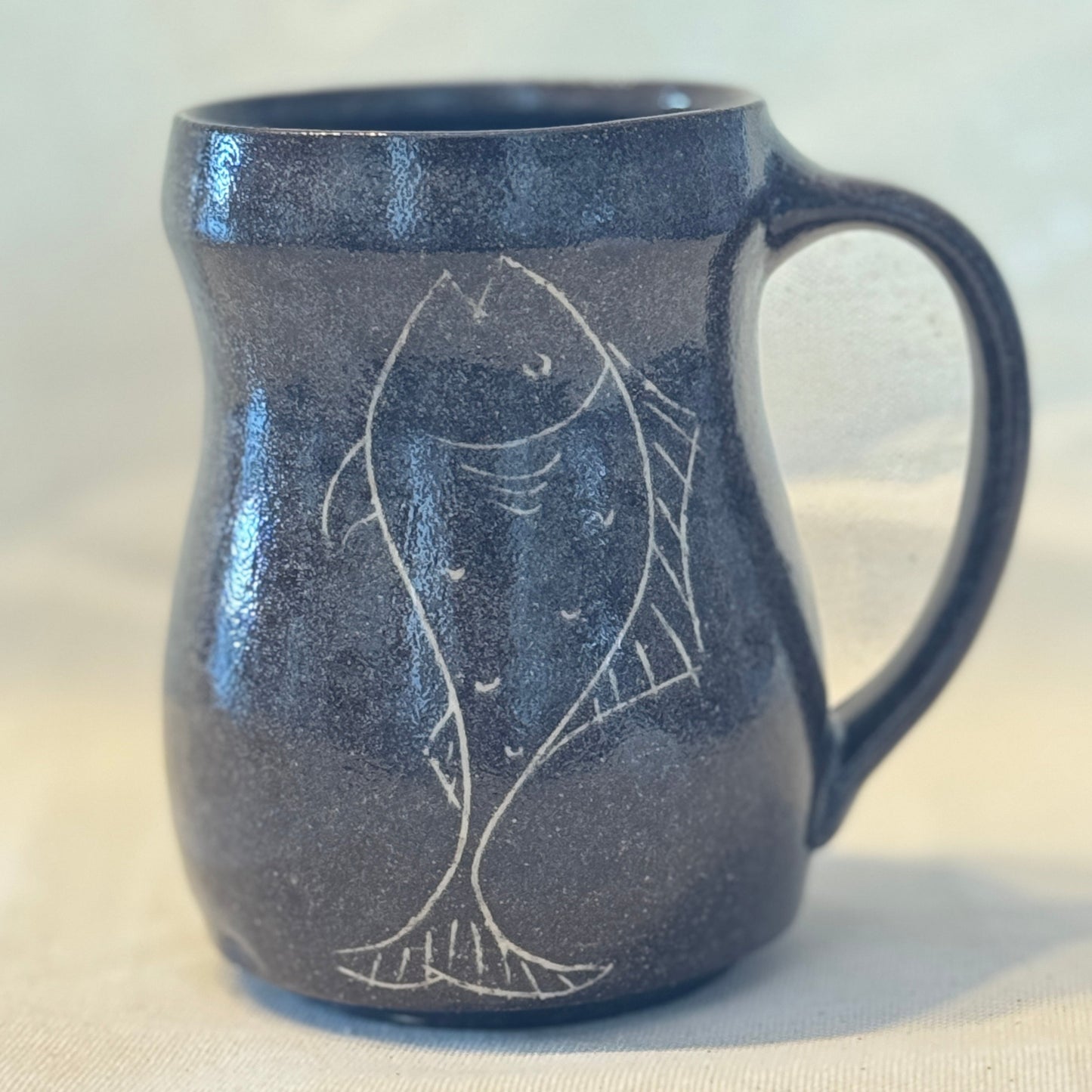 Dark blue ceramic mug with fish design on a light background