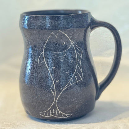 Dark blue ceramic mug with fish design on a light background
