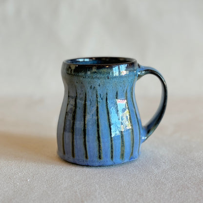 Blue ceramic mug with a textured surface on a light gray background