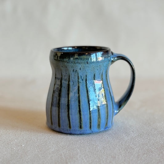 Blue ceramic mug with a textured surface on a light gray background