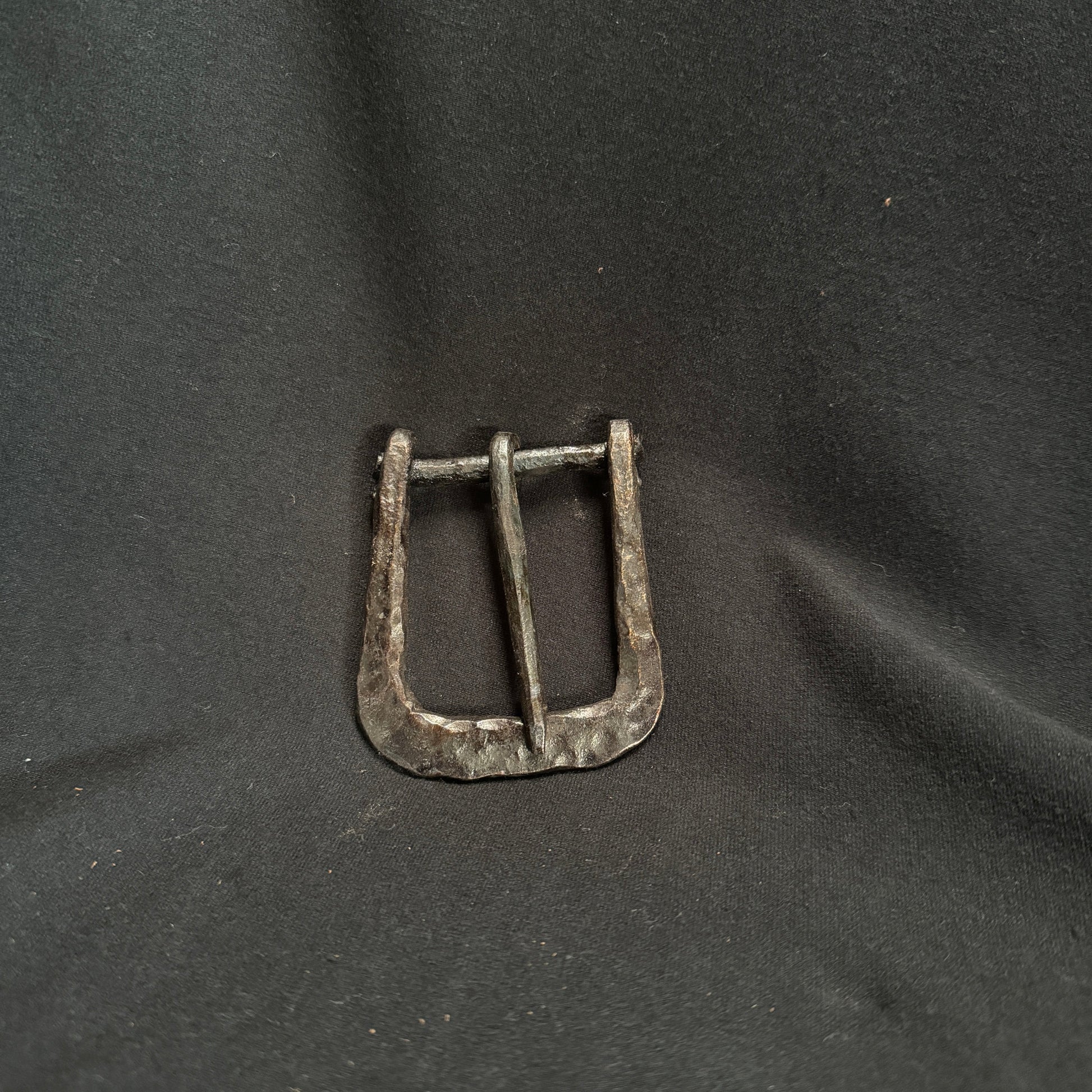 Metallic belt buckle on a dark fabric background