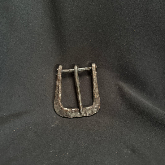 Metallic belt buckle on a dark fabric background