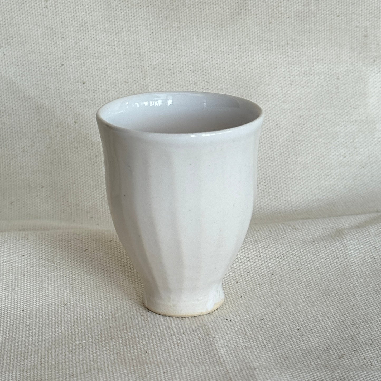White ceramic cup on a textured beige fabric background