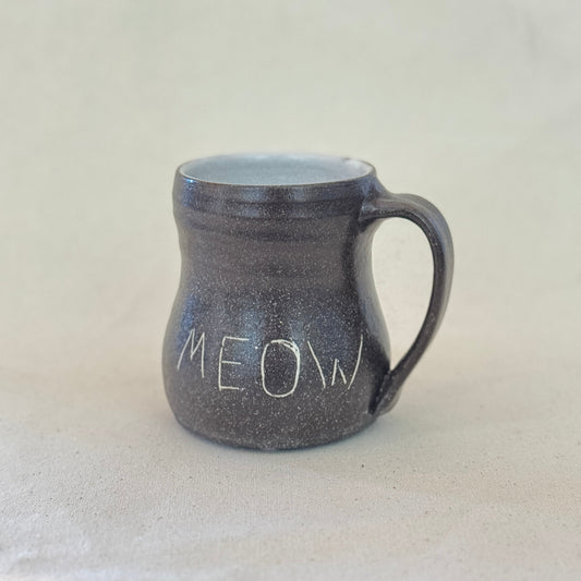 Black speckled mug with 'MEOW' text on a light gray background