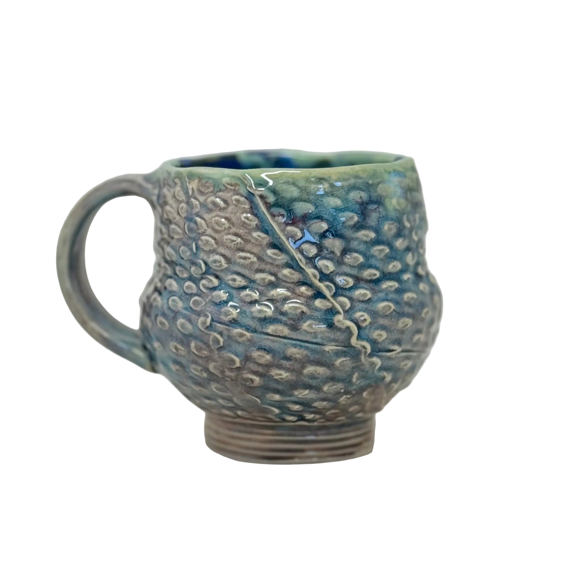 Handmade ceramic mug with textured surface on a white background