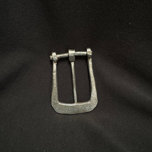 Silver belt buckle on a black fabric background